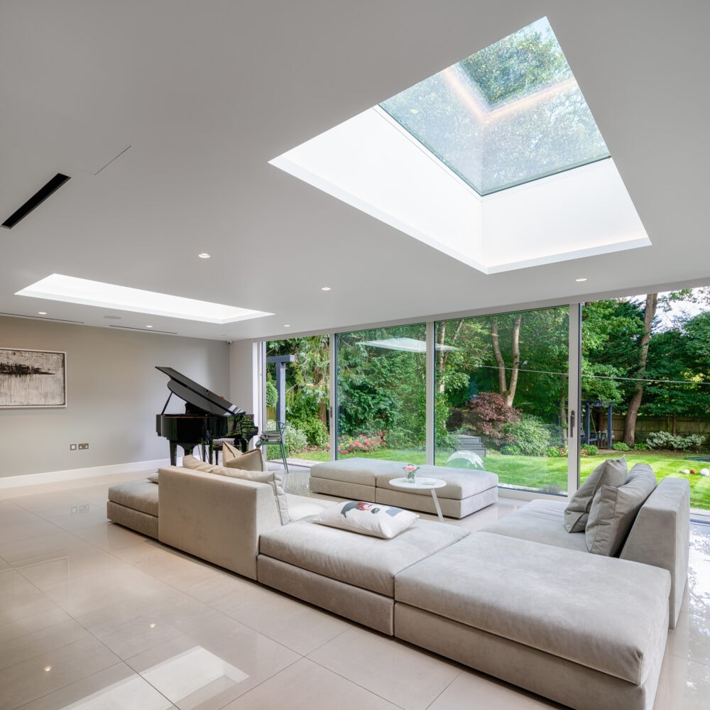 Open plan living space with larger sofa, piano, and sliding windows giving access to the garden