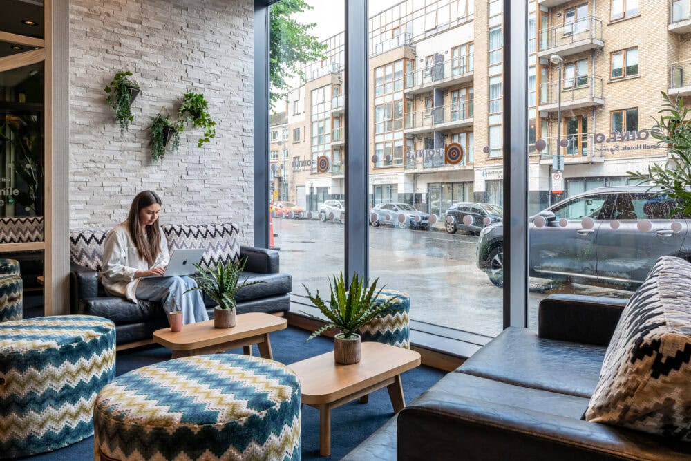 Woman sits with a laptop in the foyer of a hotel