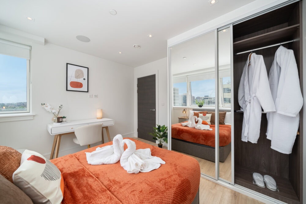 Bedroom in AirBnB apartment with robes hanging in the wardrobe
