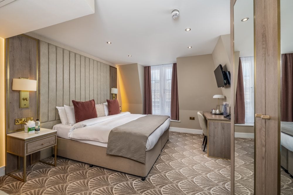 Hotel photography of a spacious hotel room featuring a bed and desk in a London Mayfair hotel.