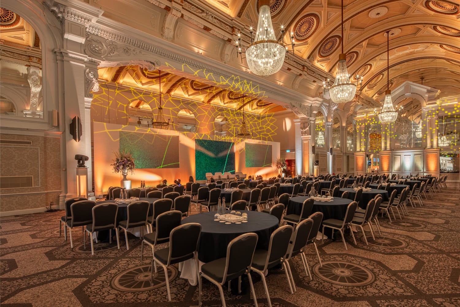 Vaulted historic events room with seating and stage set up for a conference event