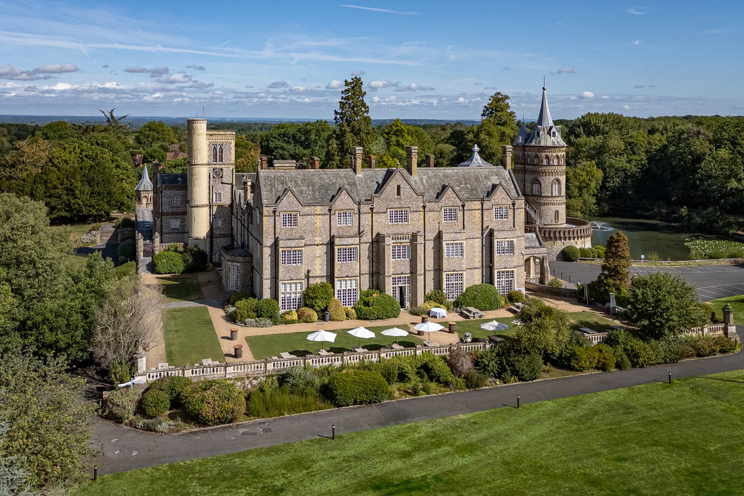 Drone exterior of a historic country house hotel with a tower and lake