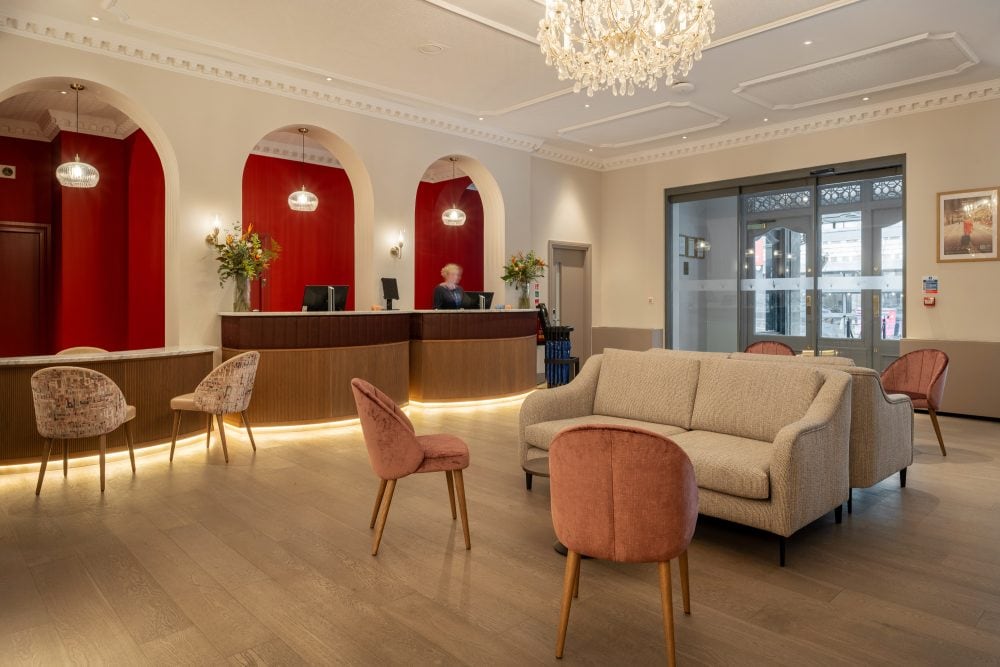 Luxurious hotel reception and lobby with long reception desk with arched wall detail behind and guest seating in the foreground